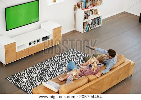 High Angle View Of Family Sitting On Sofa In Lounge Watching TV