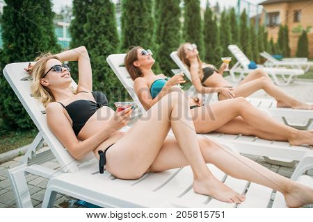 Three girls relax and sunbathig on deck chairs