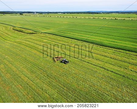 Aerial View Of Farmer On Tractor Swathing The Field For Harvest