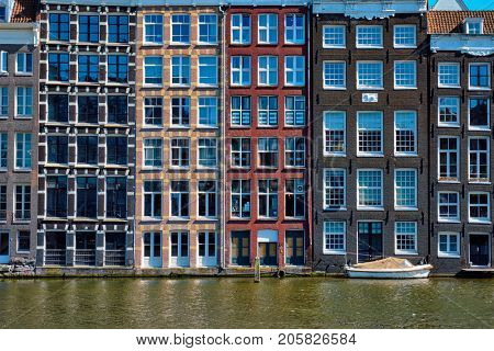 Row of typical houses and boat on Amsterdam canal  Damrak with reflection. Amsterdam, Netherlands