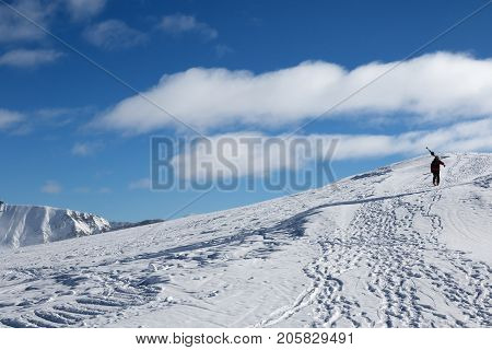 Skier with skis on his shoulder go up to top of mountain in cold sun day. Caucasus Mountains in winter Georgia region Gudauri Mt. Kudebi.