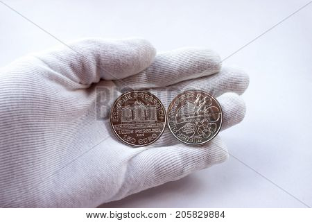 On a white glove are coins of an investment silver from a mint.