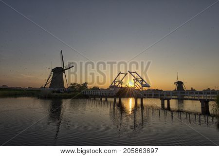 Travelling Concepts and Ideas. UNESCO Heritage Dutch Windmills and Old Bridge at Kinderdijk Located in Traditional Village in Holland The Netherlands. Plenty of Insects in The Air. Horizontal Image