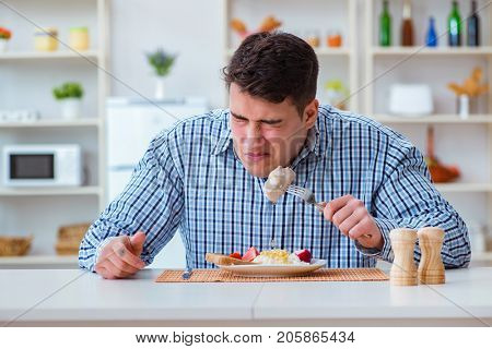 Man eating tasteless food at home for lunch