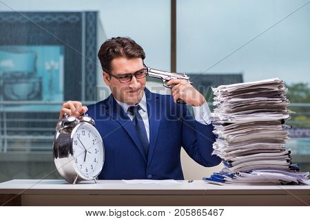 Businessman with pile stack of paper paperwork and an alarm cloc