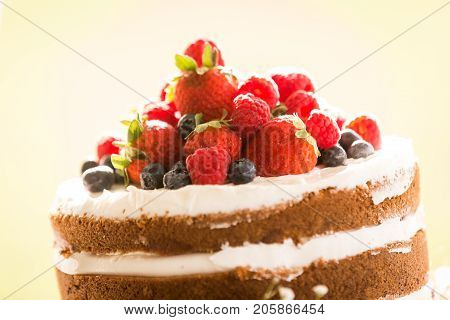 A beautiful handmade wedding cake lovingly topped with a colorful assortment of strawberries raspberries and blueberries. Close up of the top of the cake.