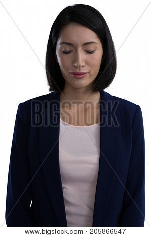 Businesswoman standing with her eyes closed against white background
