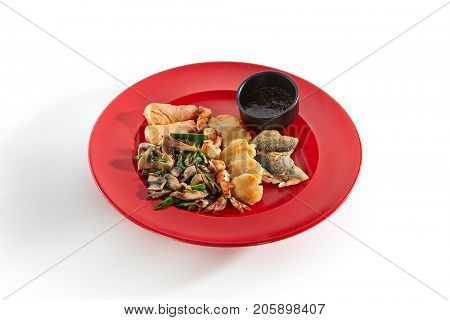 Teppanyaki Japanese and Korean Grill Food - Salmon, sea bass, shrimp 6/8, sea scallop garnished with vegetables sauce and spices on red plate on white isolated background. Asian menu