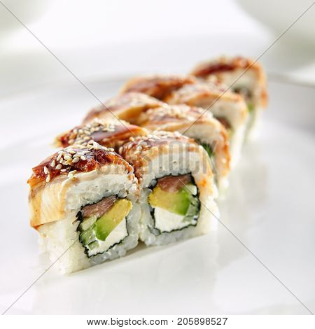 Kanada sushi rolls with salmon, eel, Philadelphia cheese, avocado and cucumber served on white flat plate. Asian menu for gourmets in luxury restaurant
