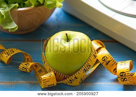 Green apple with weight scale and measuring tape for the healthy diet slimming . Diet and Healthy Concept