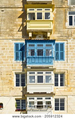 Building with traditional colorful maltese balcony in historical part of Valletta. Windows on the facade of a house in Malta