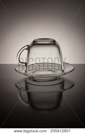 Glass transparent empty mug of tea and saucer on a black and white background