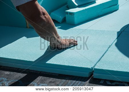 Worker placing XPS polystyrene insulation boards on the flat roof