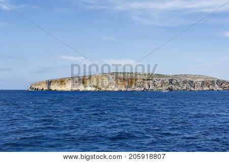 Comino is a small island of the Maltese archipelago between the islands of Malta and Gozo in the Mediterranean Sea. Pleasure craft at the rugged coastline delineated by sheer limestone cliffs and dotted with deep caves