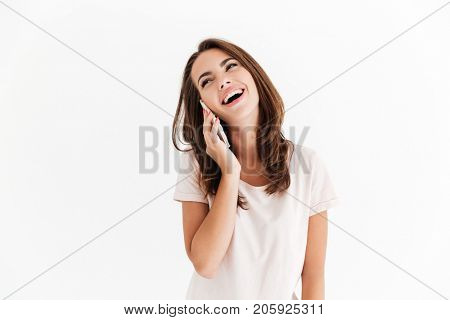 Laughing brunette woman talking by smartphone over white background