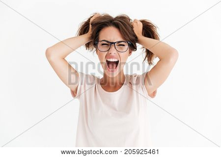 Screaming brunette woman in eyeglasses holing hair over white background