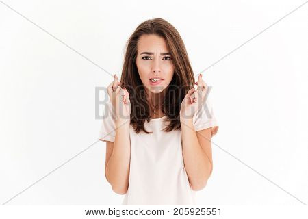 Beauty brunette woman prays for luck and looking at the camera over white background