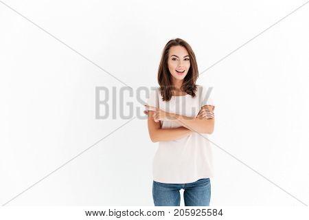 Smiling beauty woman with crossed arms pointing away and looking at the camera over white background