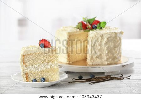 Sliced delicious vanilla cake with fresh berries on wooden table