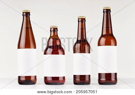 Brown beer bottles collection different type with blank white label on white wooden board mock up. Template for advertising design branding identity.
