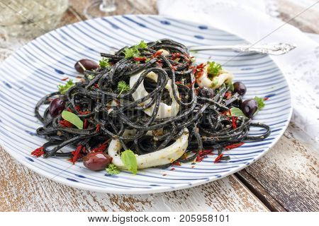 Italian linguine con tinta de calamari with olives as close-up on a plate 