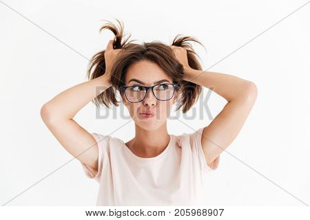 Pensive pretty woman in eyeglasses holding hair and looking away over white background
