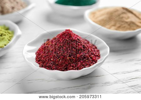 Maqui berry powder in white ceramic bowl on wooden background
