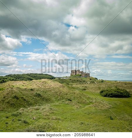 An elevated drone view of Bamburgh Castle on the coast of the north of England surrounded by natural heathland.