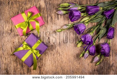 Bright gift boxes with ribbons and purple flowers. A bouquet of eustoms and a romantic gift