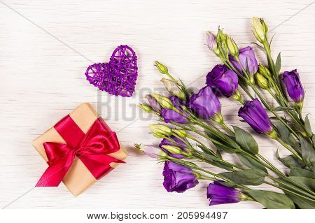 Gift box and flowers of eustoma on a white background. Romantic concept. Wicker heart.