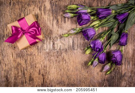 Gift box with bow and purple flowers. Eustoma. A romantic gift. Mothers Day.
