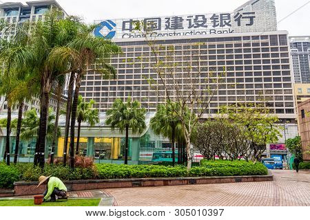 Hong Kong, China, March 2013 Chinese Gardener At Work, Maintaining Lawn In Front Of China Constructi