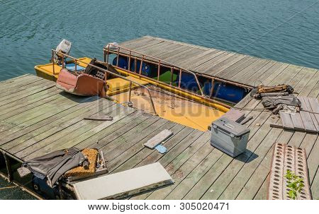 Abandoned Yellow Fishing Boat With Outboard Motor Filled With Dirty Water Docked At Wooden Pier Litt