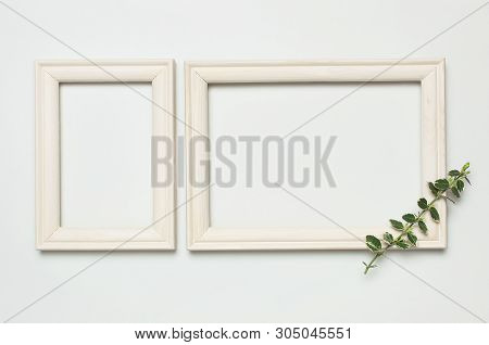 White Wooden Photo Frame And Spring Green Twigs Of Plants On Gray Background. Flat Lay Top View Copy