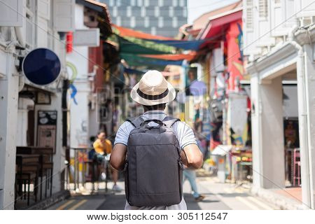 Young Man Hipster Traveling With Backpack And Hat, Happy Asian Traveler Walking At Haji Lane And Ara