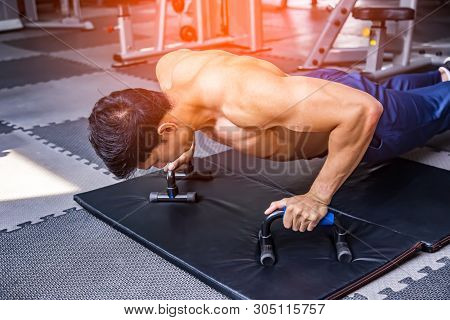 Young Couple Is Working Out At Gym. Attractive Handsome Muscular Man Are Training In Modern Gym.