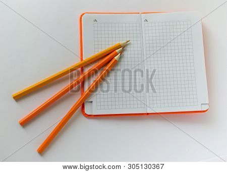 ..orange Notepad And Next To It Is An Orange Pencil On The Office Desk