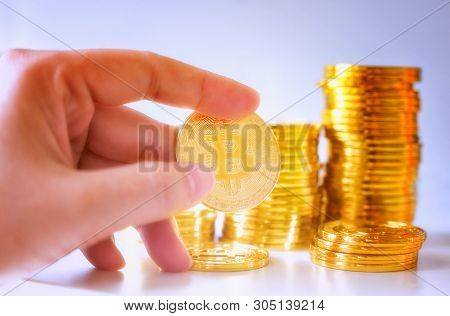 Soft Focus Hand Hold A Single Bitcoin Over Stack Of Glod Bitcoins, Cryptocurrency Concept. Virtual C