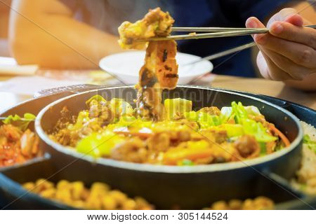 Dak Galbi Seafood On Hot Pan, Korean Food Spicy Stir-fried Chicken. Hand Use Chopsticks