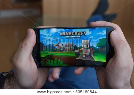 Los Angeles, California - June 3, 2019: Lying Man Holding A Smartphone And Playing Minecraft Game On