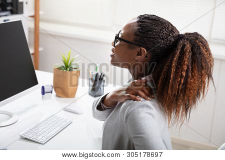 Businesswoman Suffering From Shoulder Pain While Working In Office