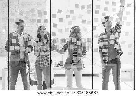 Black and White photo of Creative business colleagues using adhesive notes during brainstorming session in office