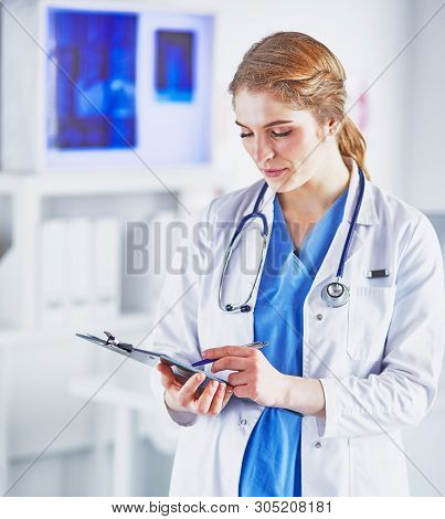 Young Woman Doctor Is Standing With Board With Clipboard Smilin