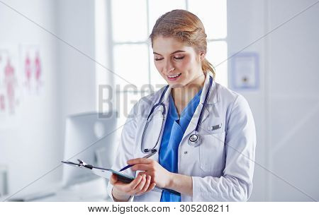 Young Woman Doctor Is Standing With Board With Clipboard Smilin