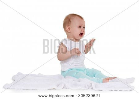 Little unhappy baby is sitting and crying on a plaid on white background. Eight months