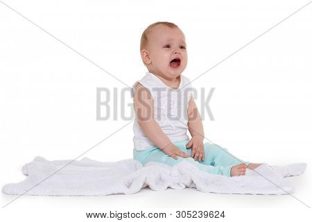 Little unhappy baby is sitting and crying on a plaid on white background. Eight months