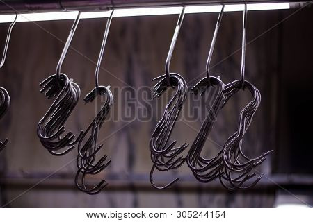 Row Of Metal Butchers Hooks Against Soft Grey Background