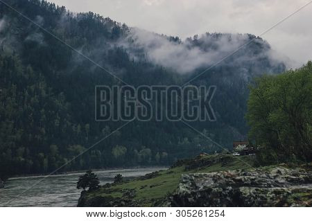 River And Forested Mountain In Fog And Cloud. Misty Landscape With Fir Forest In Dense Fog