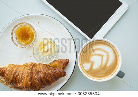 Falt Lay Of Fresh Croissant With Jam, Butter And Cappuccino With Beautiful Latte Art On Grey Table I
