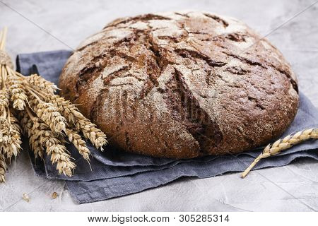 Freshly Baked Round Sourdough Bread And Rye Ears On Kitchen Table. Rustic Style. Selective Focus. Co
